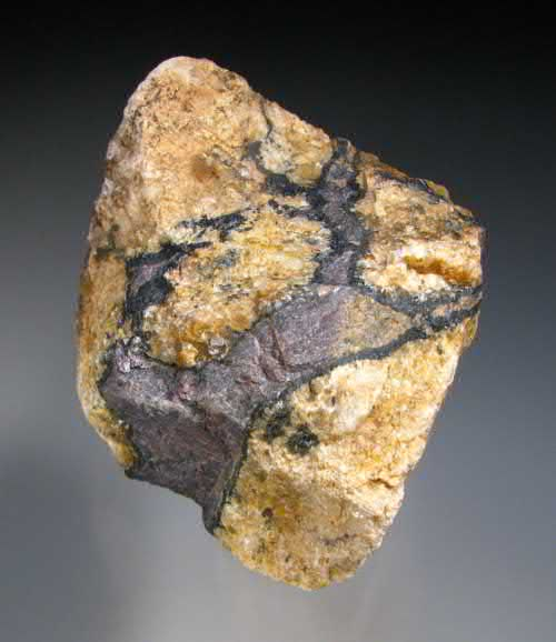 FIGURE 7.25 Undifferentiated black minerals of allanite, {Ca(Ce,La,Nd)}(Al2Fe21)(Si2O7)(SiO4)O(OH), and thorianite, ThO2, with massive, finegrained purplish britholite-(Ce), (Ce,Ca)5(SiO4)3OH.